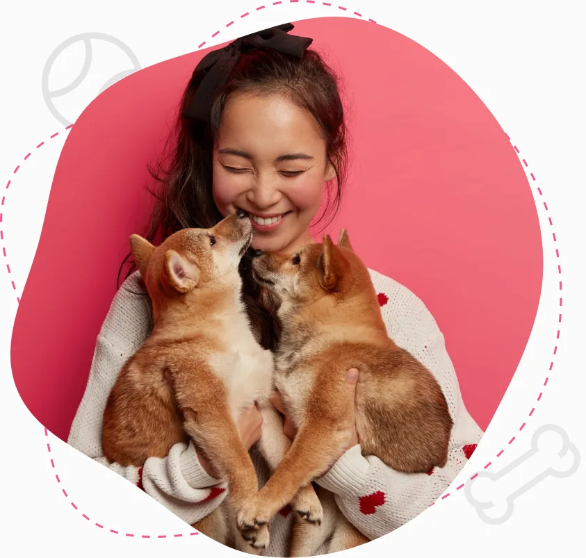 Chica abrazando a dos cachorros shiba sobre una forma rosada